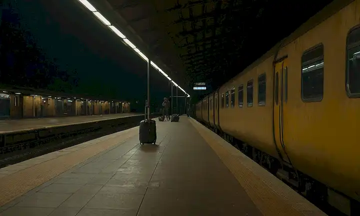 estación de tren de la noche, plataforma desierta, iluminación débil, equipaje desgastado disperso, pasajero de aspecto ansioso, fondo oscuro con toques de vida urbana fuera
